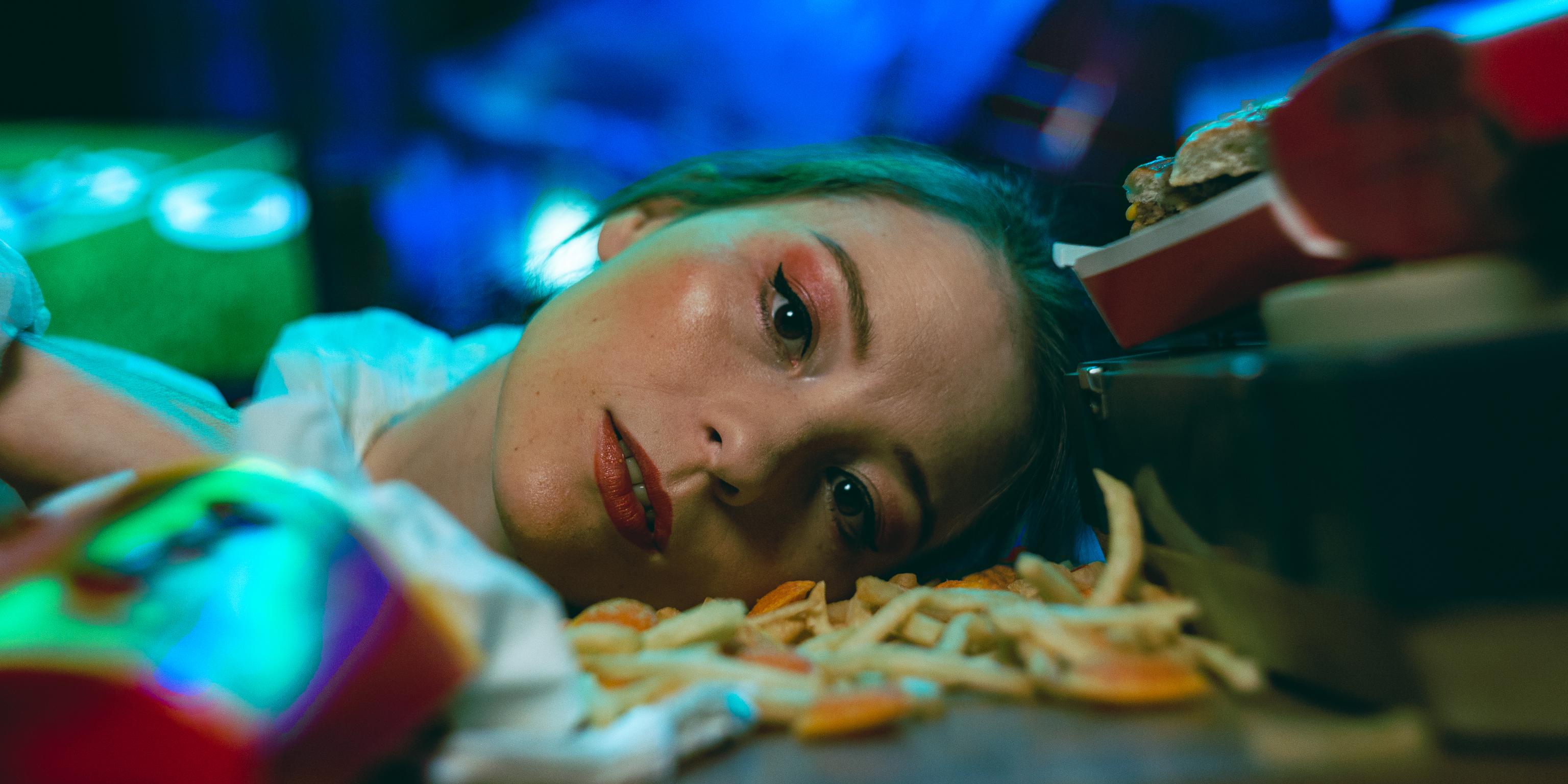 Close-up portrait of Tereza Císařová laying on a table with fries, photographed at Divadlo Na Vinohradech.