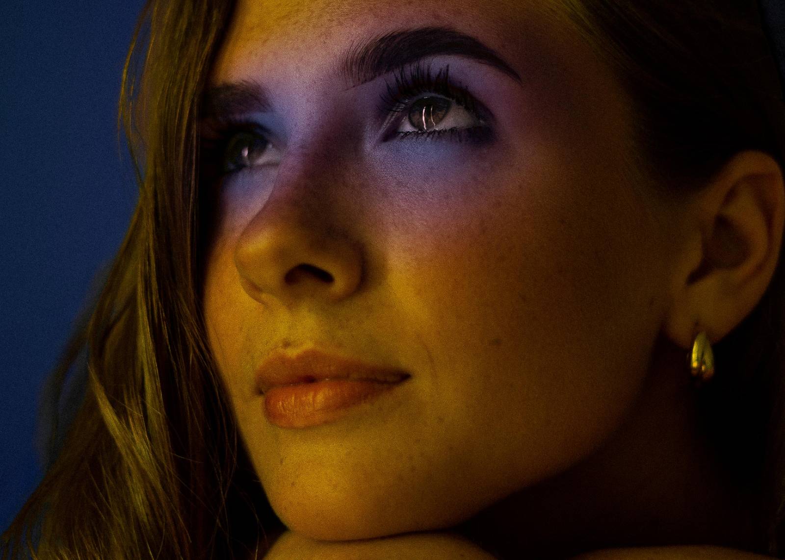 Close-up of a girl's face with colourful makeup around her eyes, making her look like a butterfly.