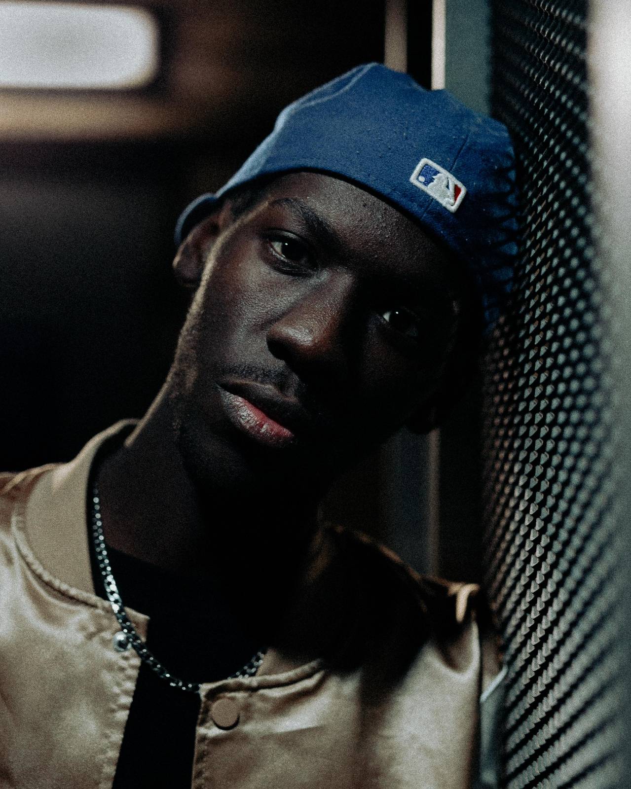 Close-up portrait of a man wearing a baseball cap leaning against a wall in Kolding.