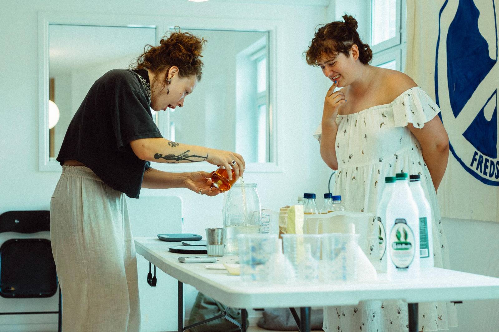 Two ladies mixing liquids in glass cups.