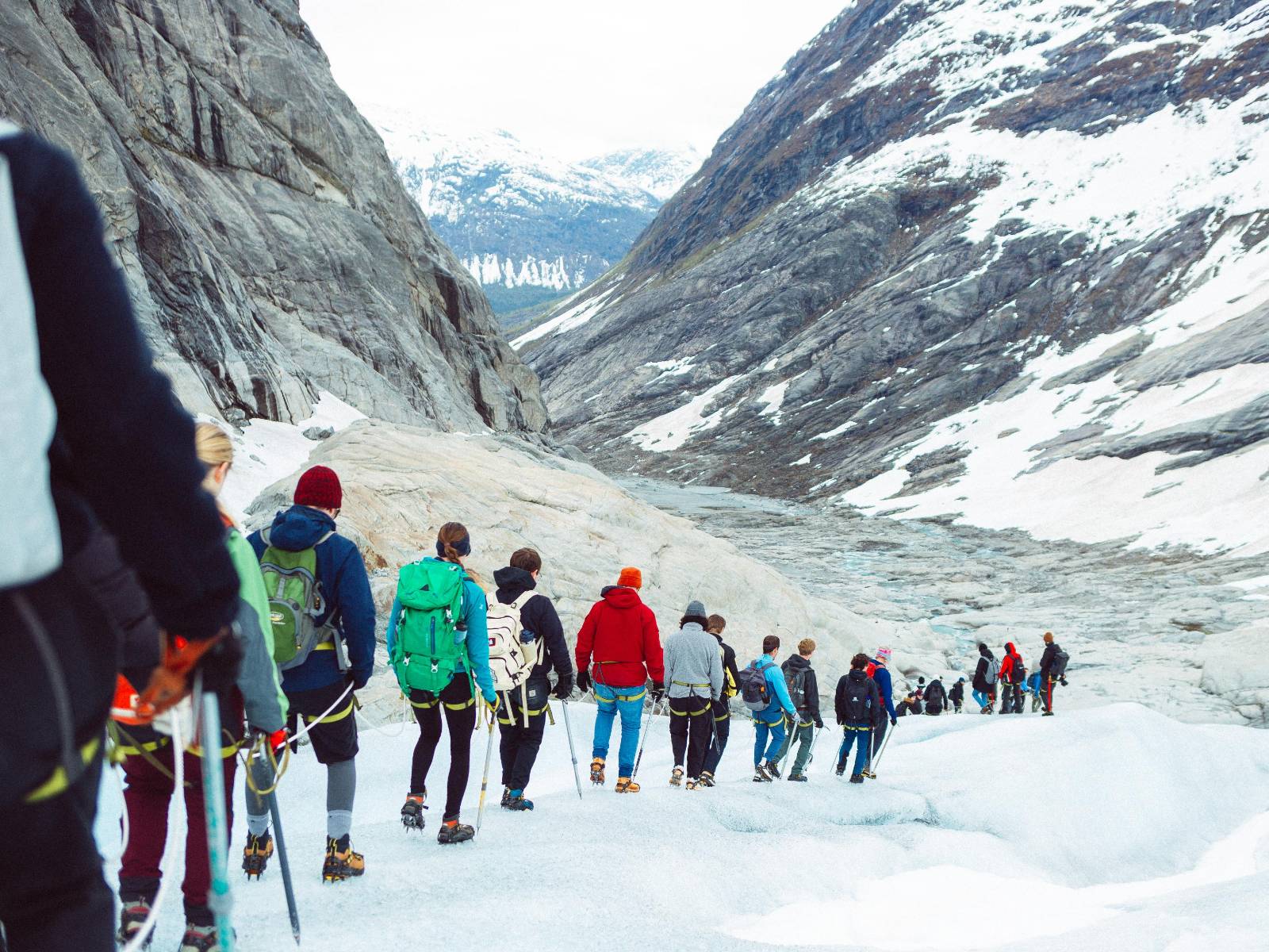 Group of hikers descending down through the valley in mountains.